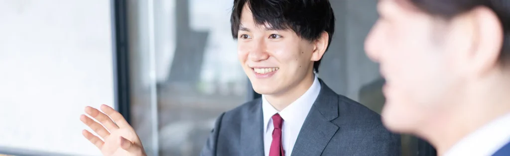 スーツ姿の男性会社員が笑顔で話している写真