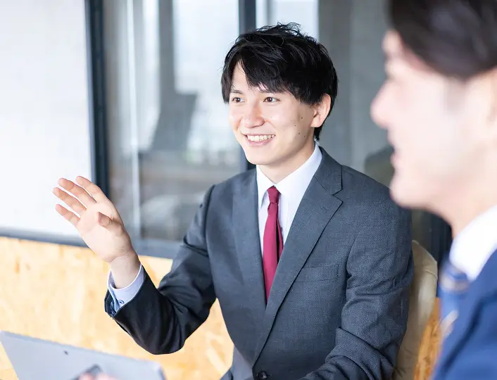 スーツ姿の男性会社員が笑顔で話している写真
